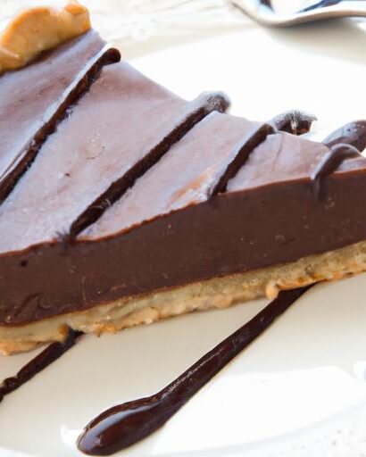 A rich chocolate ganache tart with a smooth, glossy finish, sliced and served on a plate, showcasing its decadent texture.